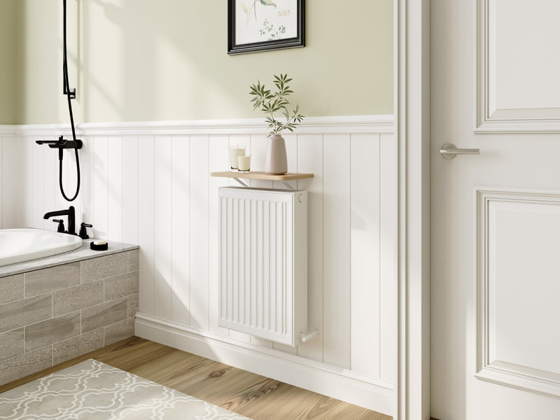 A compact oak Loby radiator shelf fitted above a small white radiator in a panelled bathroom